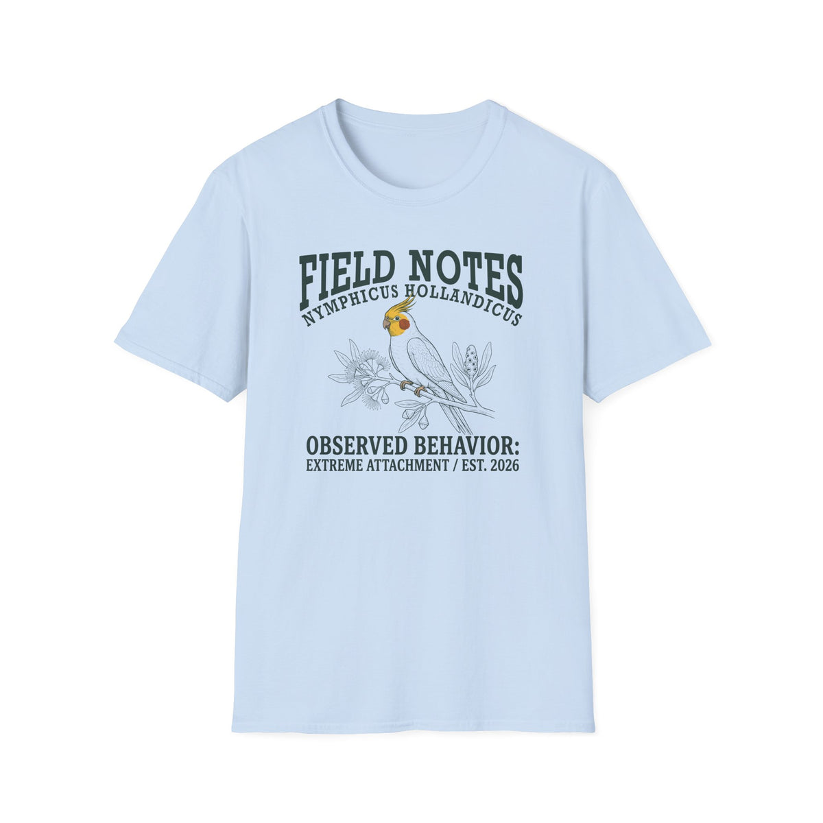 A light blue short-sleeve t-shirt with a graphic print on the front. The print features a parrot bird and the text 'FIELD NOTES', 'NYMPHICUS HOLLANDICUS', and 'OBSERVED BEHAVIOR: EXTREME ATTACHMENT / EST.